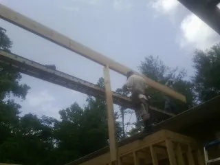 Carpenter setting a ridge beam over a new addition frame — Ice Dam Removal by Roofing Brothers in King George