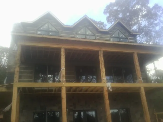 Dormers and porch framing on a large log home under construction — Roof Coating work by our crew in King George