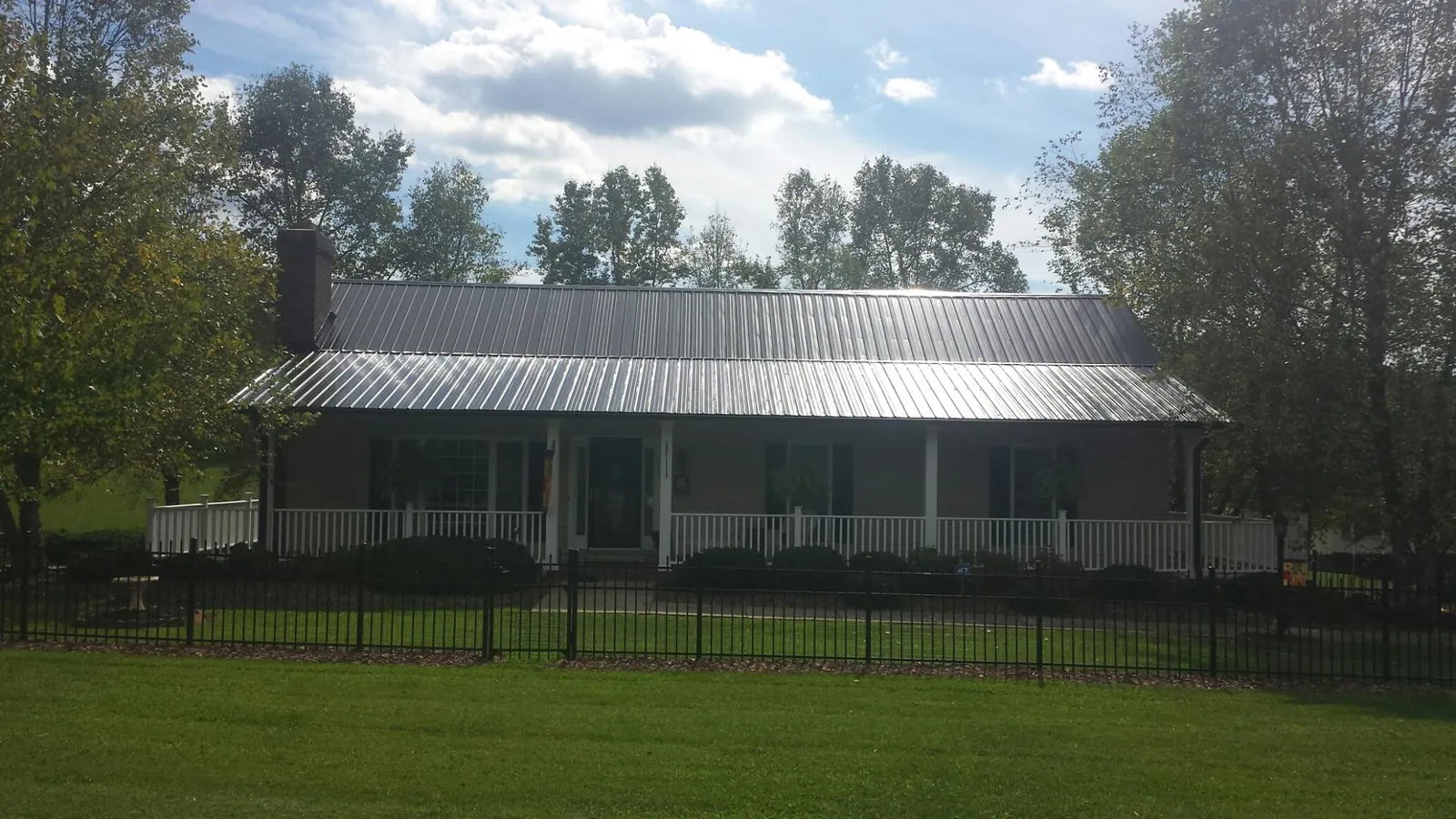 Gray metal roof on a brick ranch with a full width front porch — Gutter Guard Installation work by our crew in King George