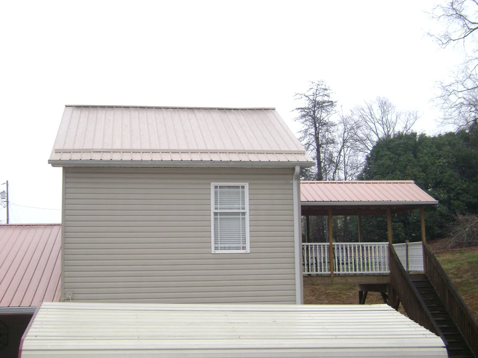 Tan metal roofs on a two story addition and attached porch, from a Roof Replacement job in King George