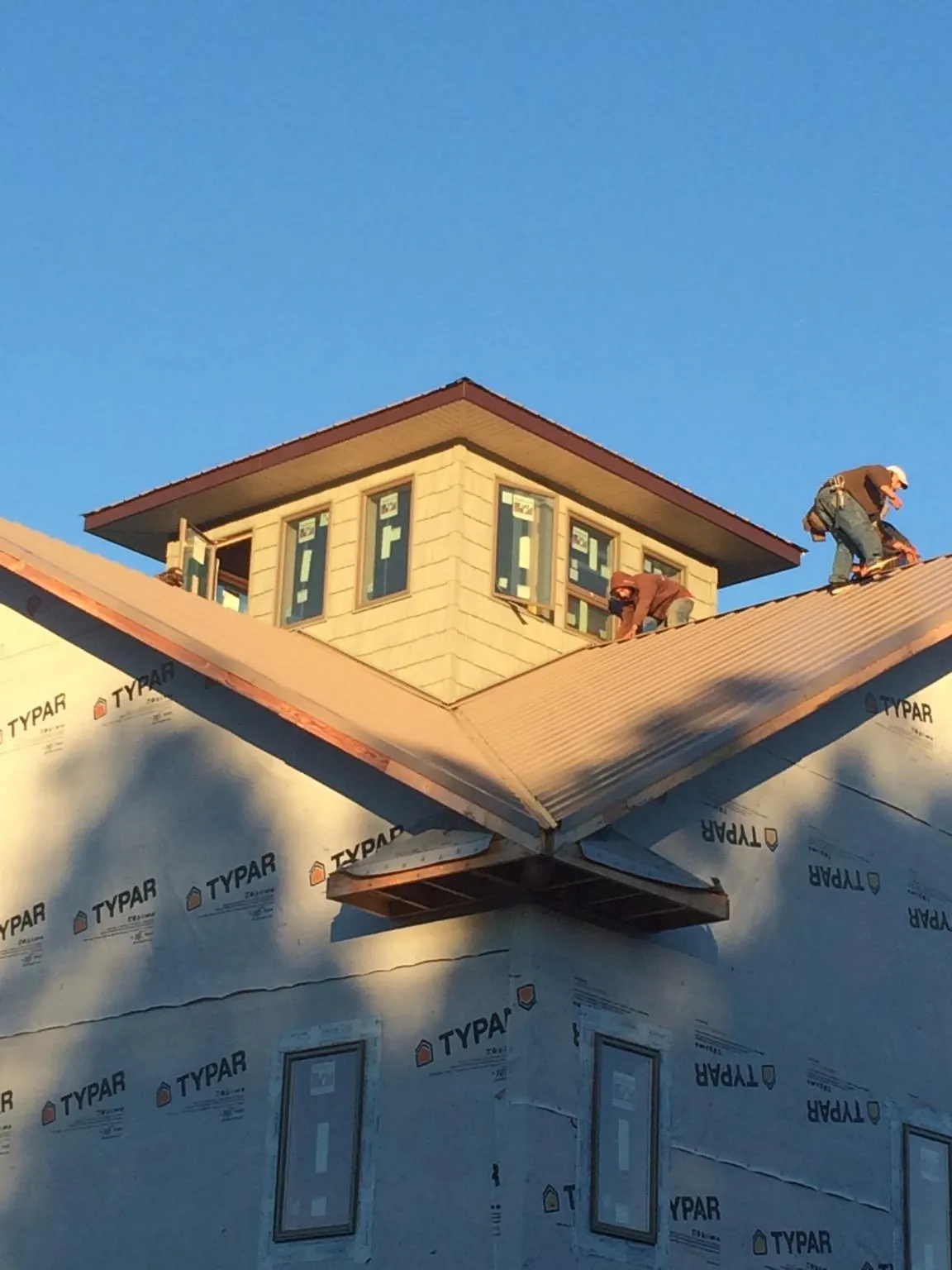 Roofers working around a rooftop cupola on a new metal roof at sunset — Roof Waterproofing in King George by Roofing Brothers